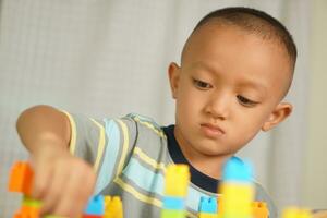 Asian boy playing with educational toys There are many beautiful colors on the table in the house. photo