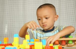 Asian boy playing with educational toys There are many beautiful colors on the table in the house. photo