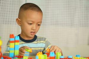 Asian boy playing with educational toys There are many beautiful colors on the table in the house. photo