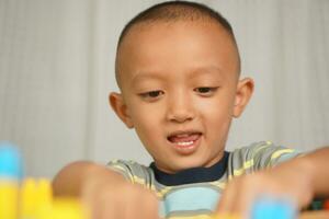 Asian boy playing with educational toys There are many beautiful colors on the table in the house. photo