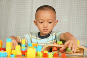 Asian boy playing with educational toys There are many beautiful colors on the table in the house. photo