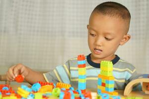 Asian boy playing with educational toys There are many beautiful colors on the table in the house. photo