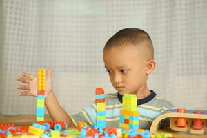 Asian boy playing with educational toys There are many beautiful colors on the table in the house. photo