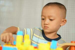 Asian boy playing with educational toys There are many beautiful colors on the table in the house. photo