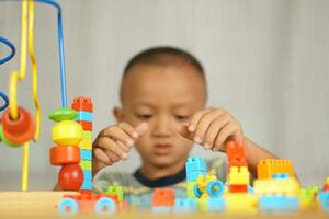 Asian boy playing with educational toys There are many beautiful colors on the table in the house. photo