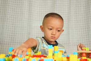 Asian boy playing with educational toys There are many beautiful colors on the table in the house. photo