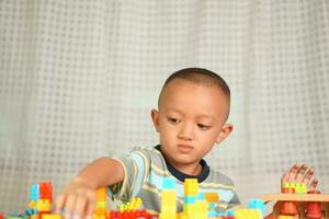 asiático chico jugando con educativo juguetes allí son muchos hermosa colores en el mesa en el casa. foto