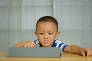 A boy watches a lesson on a portable computer. photo