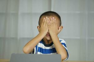 Boy has eye strain from looking at computer for a long time photo