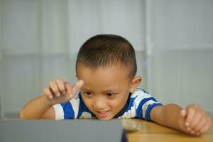 A boy watches a lesson on a portable computer. photo