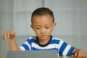 A boy watches a lesson on a portable computer. photo