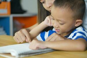 Mother teaching son to do homework photo