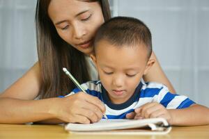 Mother holds hands with son to practice writing letters photo