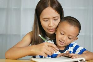 madre sostiene manos con hijo a práctica escritura letras foto