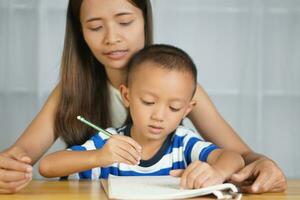 Mother teaching son to do homework photo