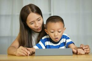 contento madre y hijo desde acecho películas juntos en un portátil computadora foto