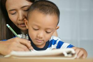 Mother holds hands with son to practice writing letters photo