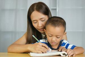 madre sostiene manos con hijo a práctica escritura letras foto
