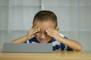Boy has eye strain from looking at computer for a long time photo