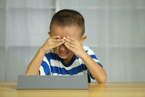 Boy has eye strain from looking at computer for a long time photo