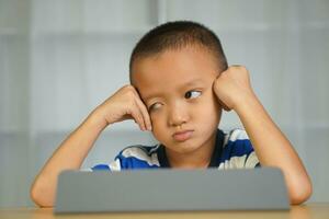 un chico es aburrido porque él mira a el computadora para un largo tiempo. foto