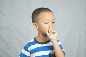 Asian boy sticks finger into nose photo