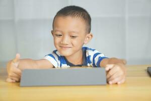 chico sentado felizmente estudiando en línea foto