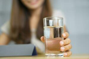 Asian woman working at home holding a glass of water in hand photo
