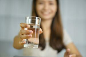 Asian woman working at home holding a glass of water in hand photo