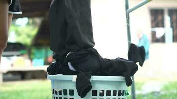 woman picks up a basket of washed clothes to dry in the sun. video