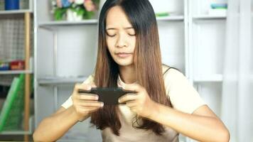 vrouw gebruik makend van telefoon naar Speel spellen Bij huis bureau video