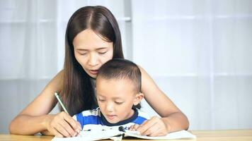 Mother holds hands with son to practice writing letters video