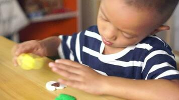 Boy making plasticine to promote development on the table in the house. video