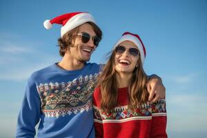 un cerca arriba foto de un joven Pareja vistiendo Navidad suéteres y Papa Noel sombreros en pie solo en un azul fondo, ai generativo