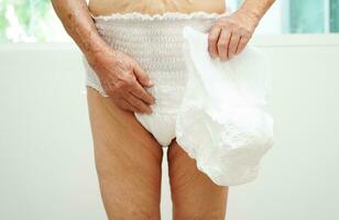 Asian senior woman patient wearing adult incontinence diaper pad in hospital. photo