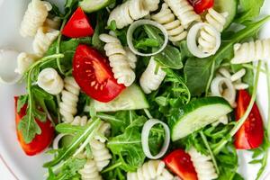 pasta salad fusilli pasta, cucumber, tomato, green lettuce, onion delicious healthy eating cooking appetizer meal food snack on the table copy space food background photo