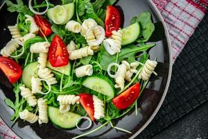 pasta salad fusilli pasta, cucumber, tomato, green lettuce, onion healthy eating cooking appetizer meal food snack on the table copy space food background rustic top view photo
