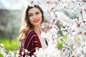 soleado primavera retrato de contento joven mujer riendo y posando cerca flor árbol. foto