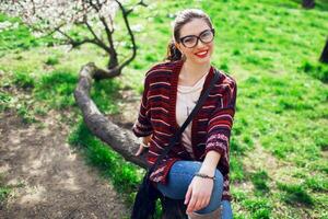 soleado primavera retrato de contento joven mujer riendo y posando cerca flor árbol. foto