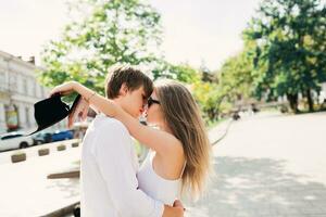 Romantic emotional portrait of two lovers, amazing couple in white spring outfit hugging on street, long blonde hairs. Vintage  soft toned colors. photo