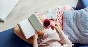 Close up indoor portrait of graceful blonde woman enjoying smell of cappuccino  , dreaming and looking into the window.  Wearing pink knitted sweater. photo