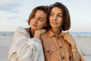 Summer fashion image of two  brunette european women in linen clothes posing on the beach photo