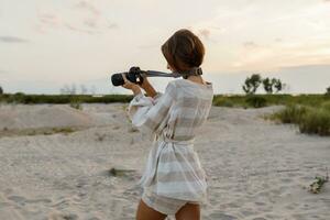 hermosa europeo mujer con corto pelos demostrar de moda verano Mira yo en el playa. lino ropa. Paja sombrero. foto