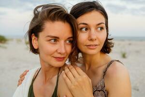 Summer fashion image of two  brunette european women in linen clothes posing on the beach photo