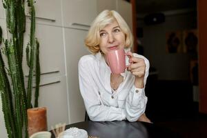 Attractive middle-aged blonde  woman relaxing at home on the kitchen photo