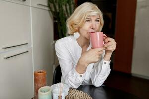 Attractive middle-aged blonde  woman relaxing at home on the kitchen photo