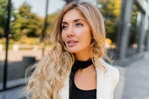 Close up portrait of stylish  pretty blond woman with perfect wavy hairs and full lips in casual jacket posing over modern stree. photo
