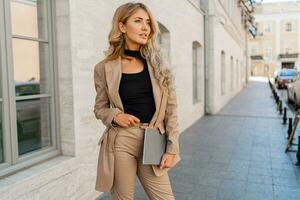 Outdoor photo of beautiful blond  student woman with wavy hairs   in casual outfit posing outdoor with notebooks. Business and study concept.