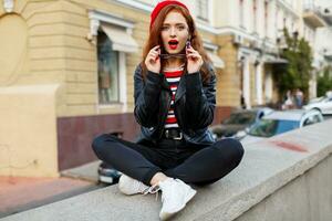 Stylish young  ginger woman in red beret and glasses posing on the street. photo