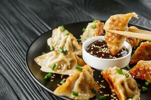 delicious fried gyoza dumplings on a black plate photo